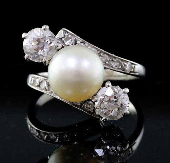 A modern white gold, natural pearl and two stone diamond crossover ring with diamond set shoulders, size K.